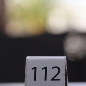 Minimalistic photo of table number 112 on a restaurant table with blurred background.