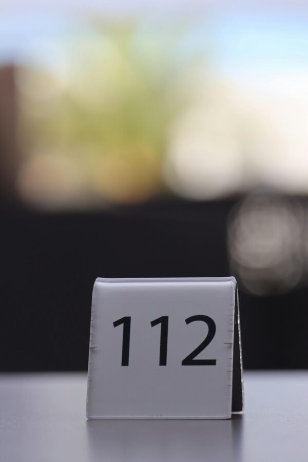 Minimalistic photo of table number 112 on a restaurant table with blurred background.